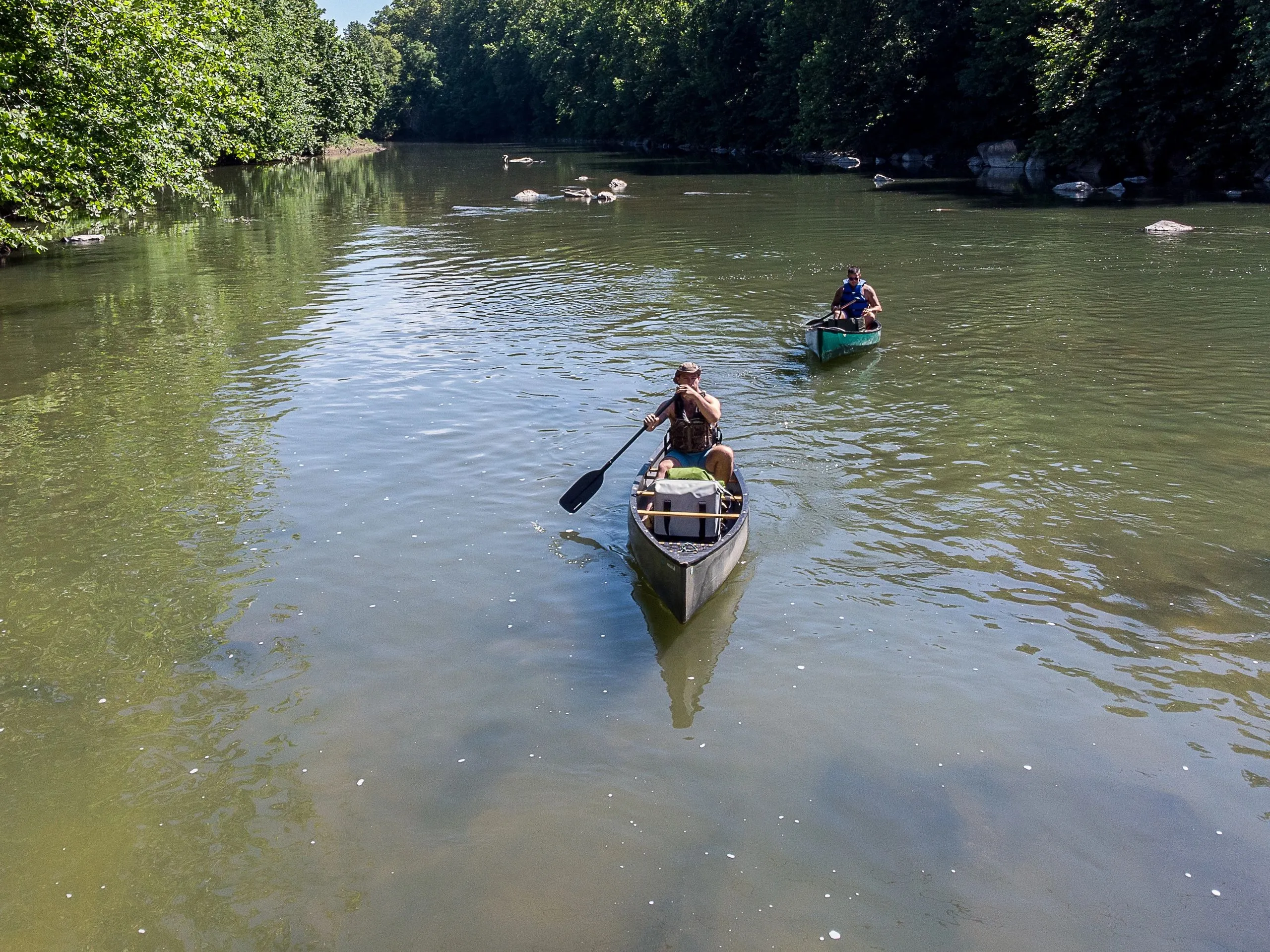 A pair of canoeists paddling on the James River near Glasgow, forested hills along the bank.