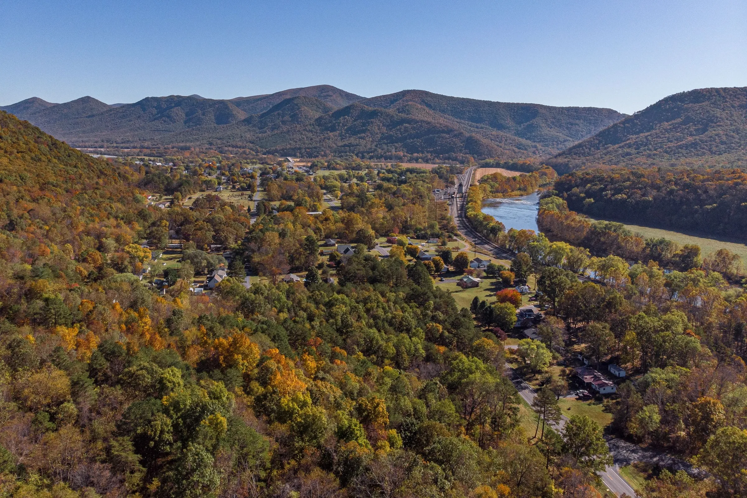 Aerial view of Glasgow, Virginia in autumn — the town nestled in a valley between Blue Ridge ridges with the James River winding past fall foliage.